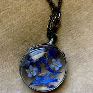 Habdcrafted glass necklace with purple and blue pressed flowers.